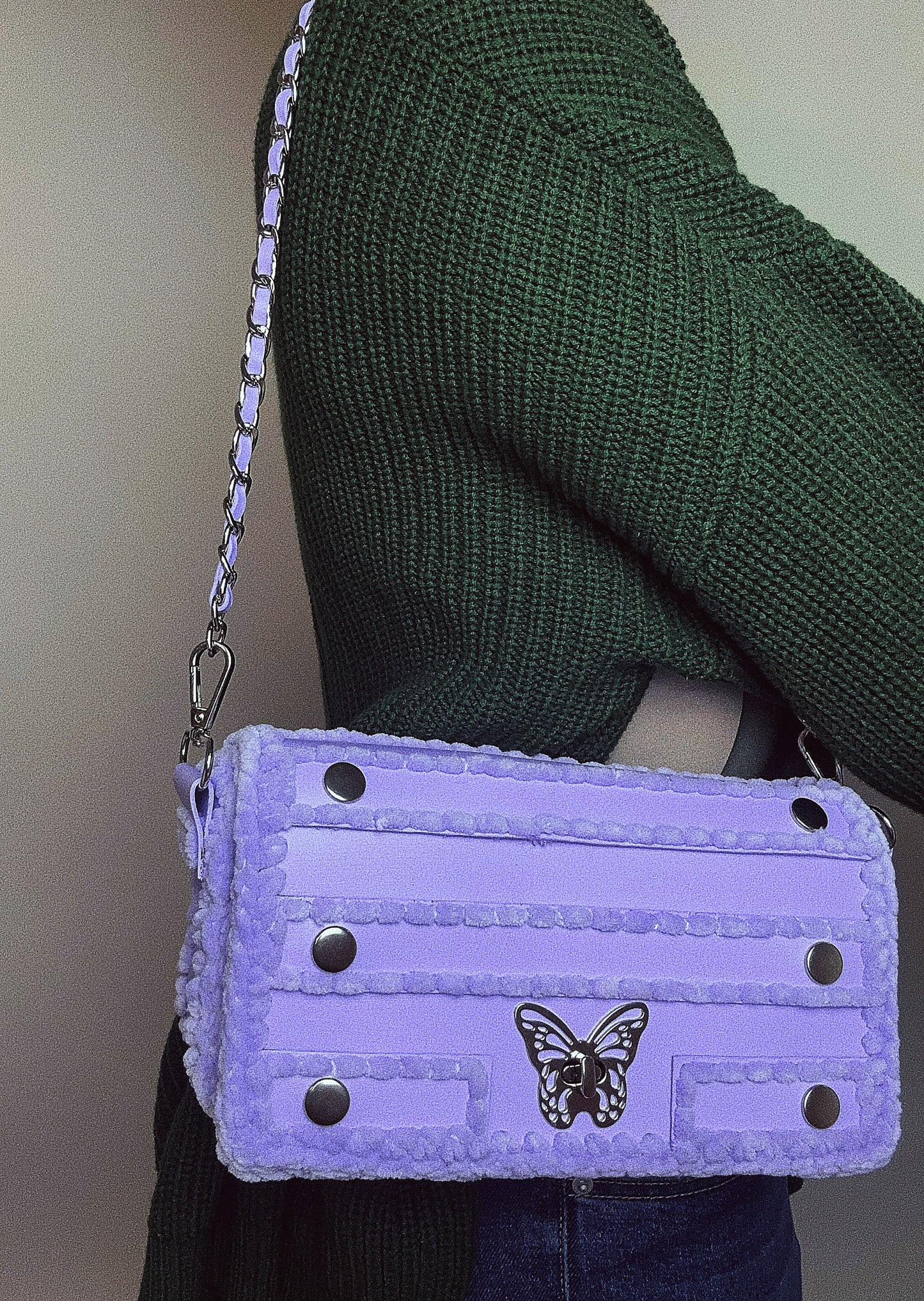 purple handbag with chain and butterfly ornament.