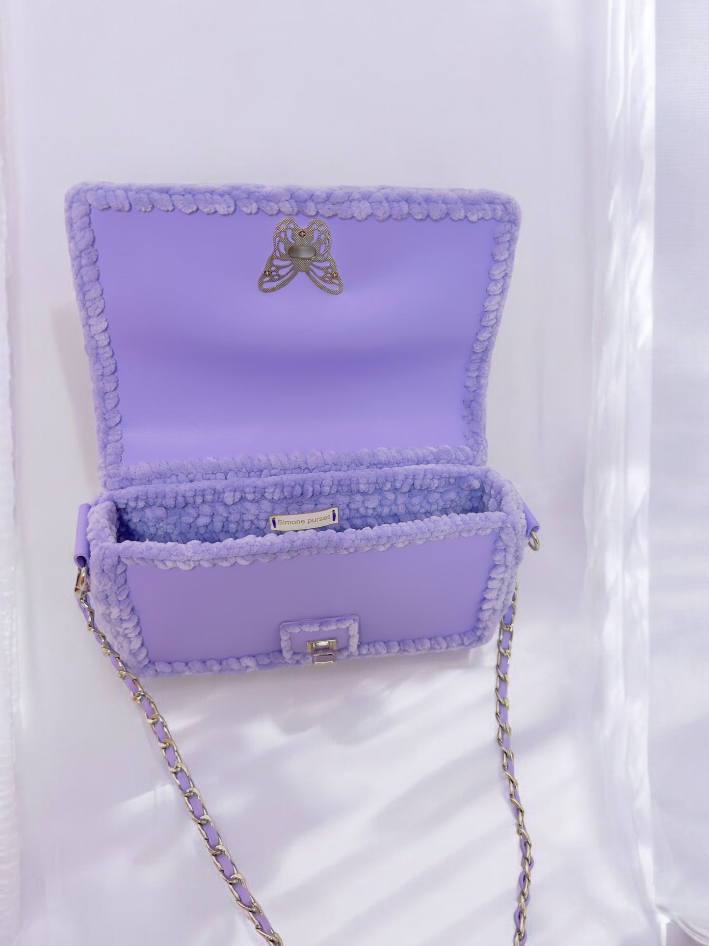 purple handbag with chain and butterfly ornament.