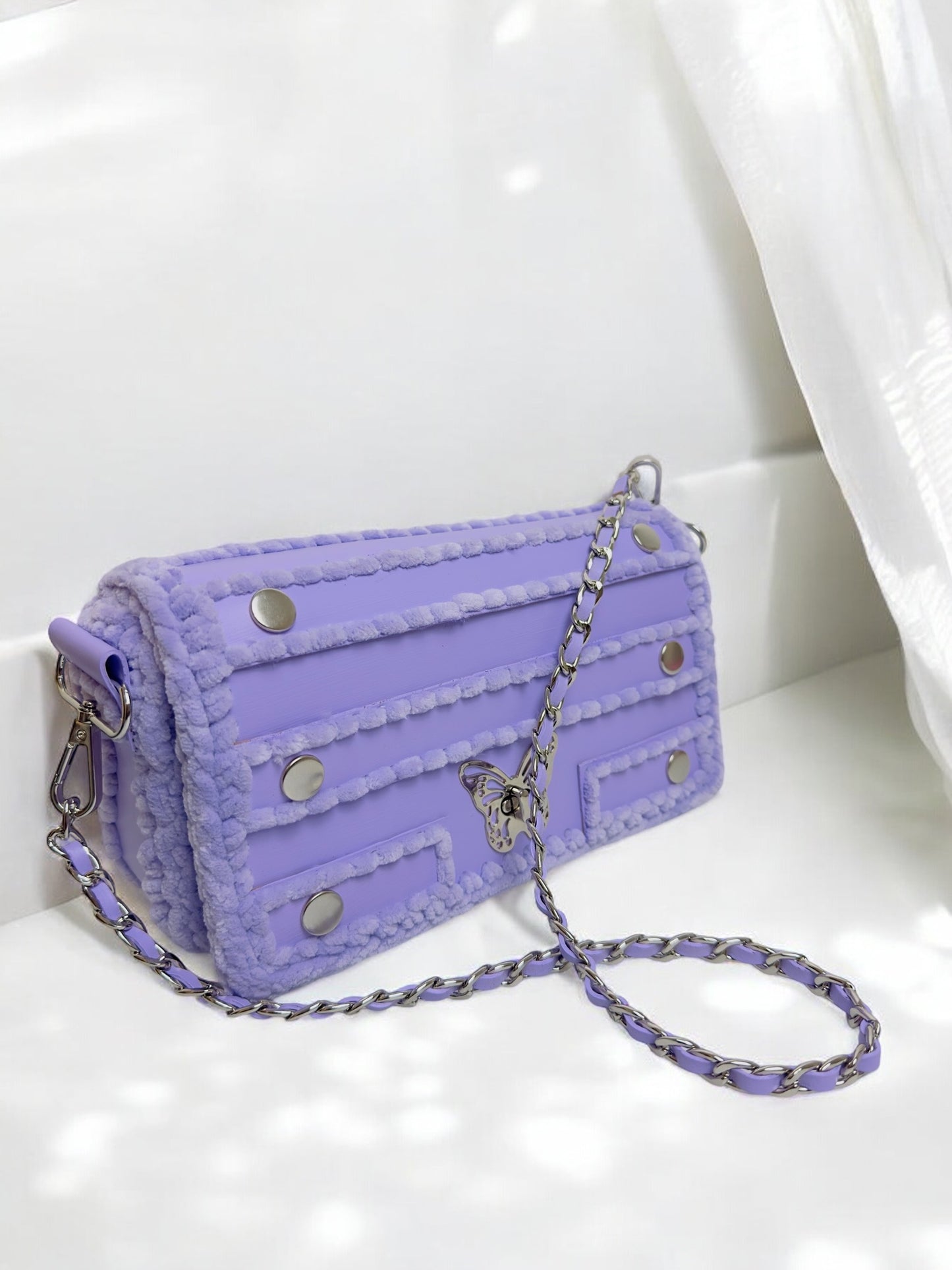 purple handbag with chain and butterfly ornament.